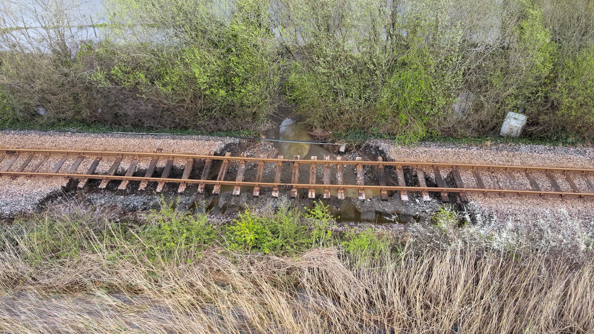 Washout / flooding damage to railway tracks leaving them suspended in the air as ballast has been washed away.